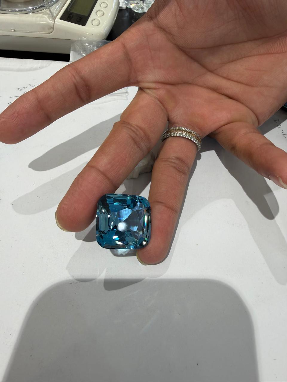 Aquamarine being weighed by hand on a digital scale