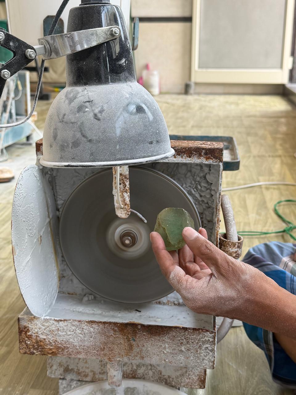 Rough aquamarine held up to the faceting wheel