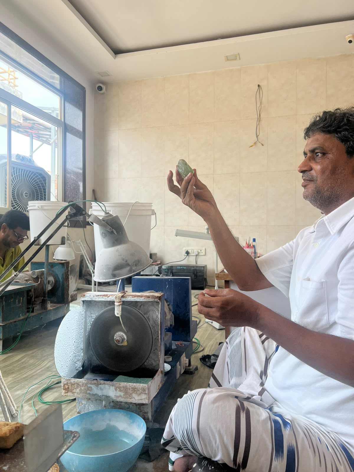 Cutter inspecting a piece of rough aquamarine by the window